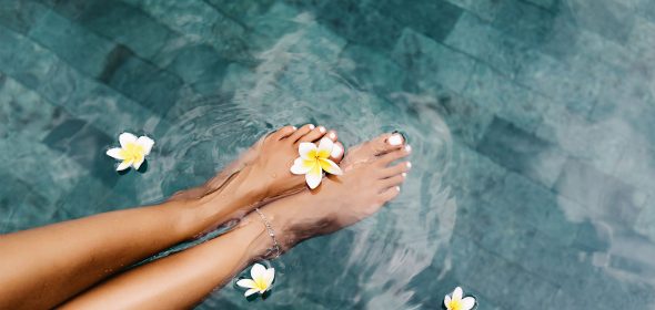 Feet dipped in a serene freshwater pool, creating a relaxing and refreshing experience.
